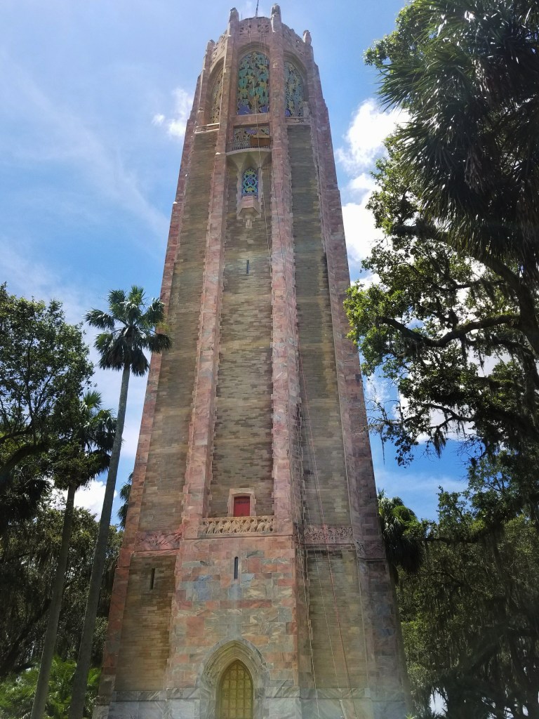 Botanical Gardens in Florida Bok Tower Gardens Singing Tower against blue sky with trees on either side.