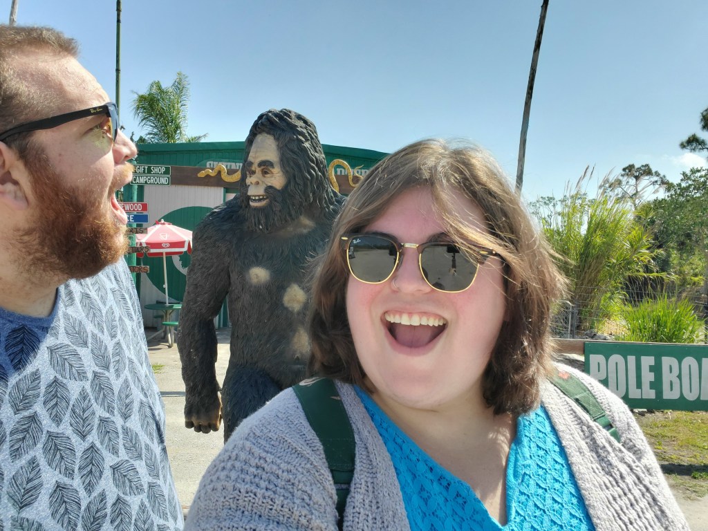 two people standing with state of skunk ape in front of a building